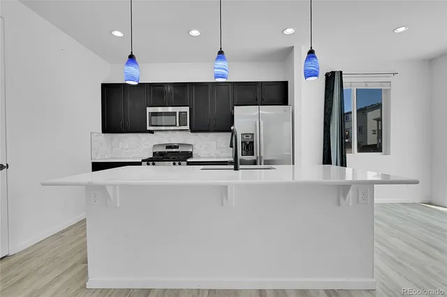a kitchen with kitchen island a refrigerator and a sink