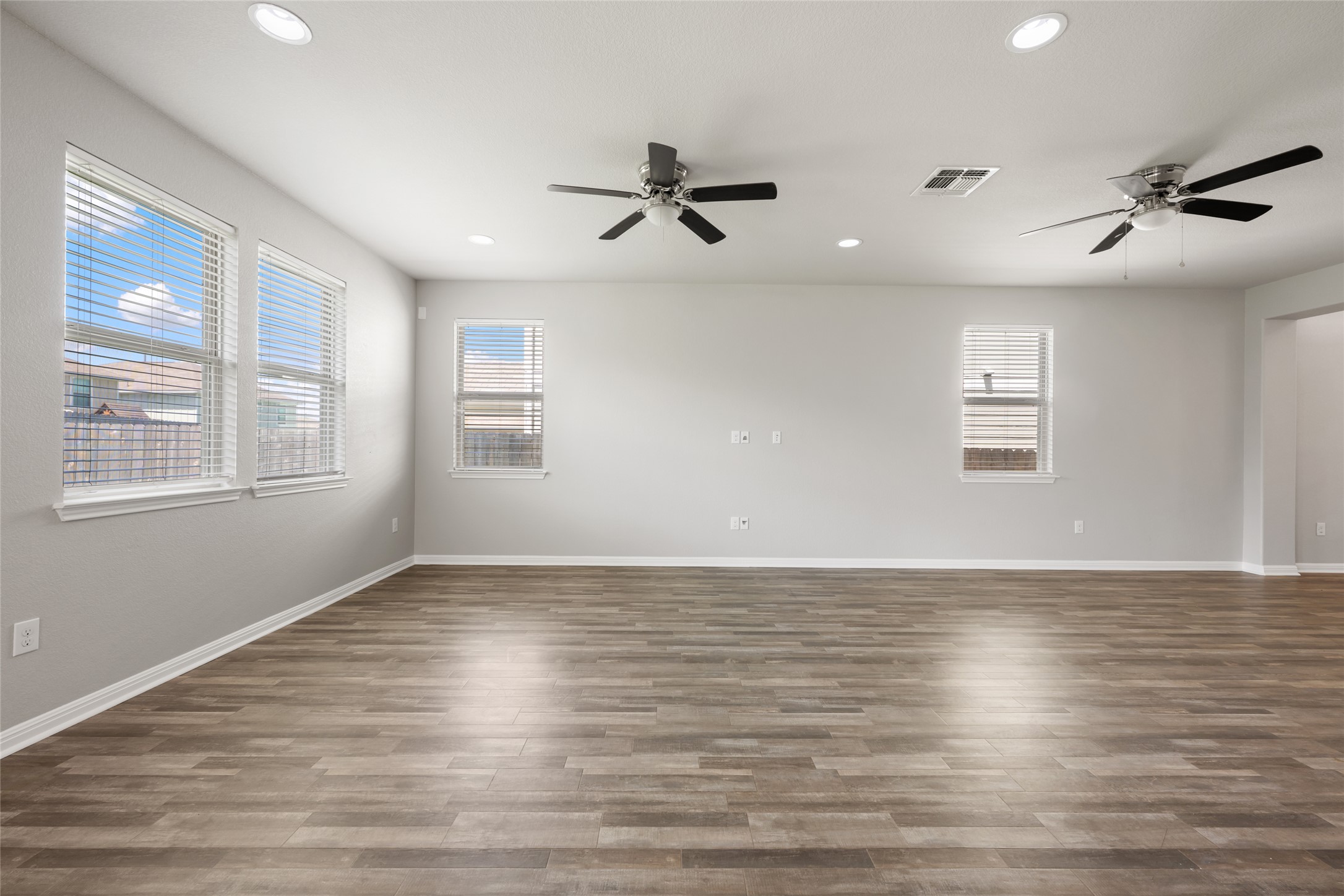 124 Guemal Road Buda, TX 78610 - Photo 10 of 40 Sun-filled living space offers wood-look flooring and two ceiling fans, ensuring comfort and style.