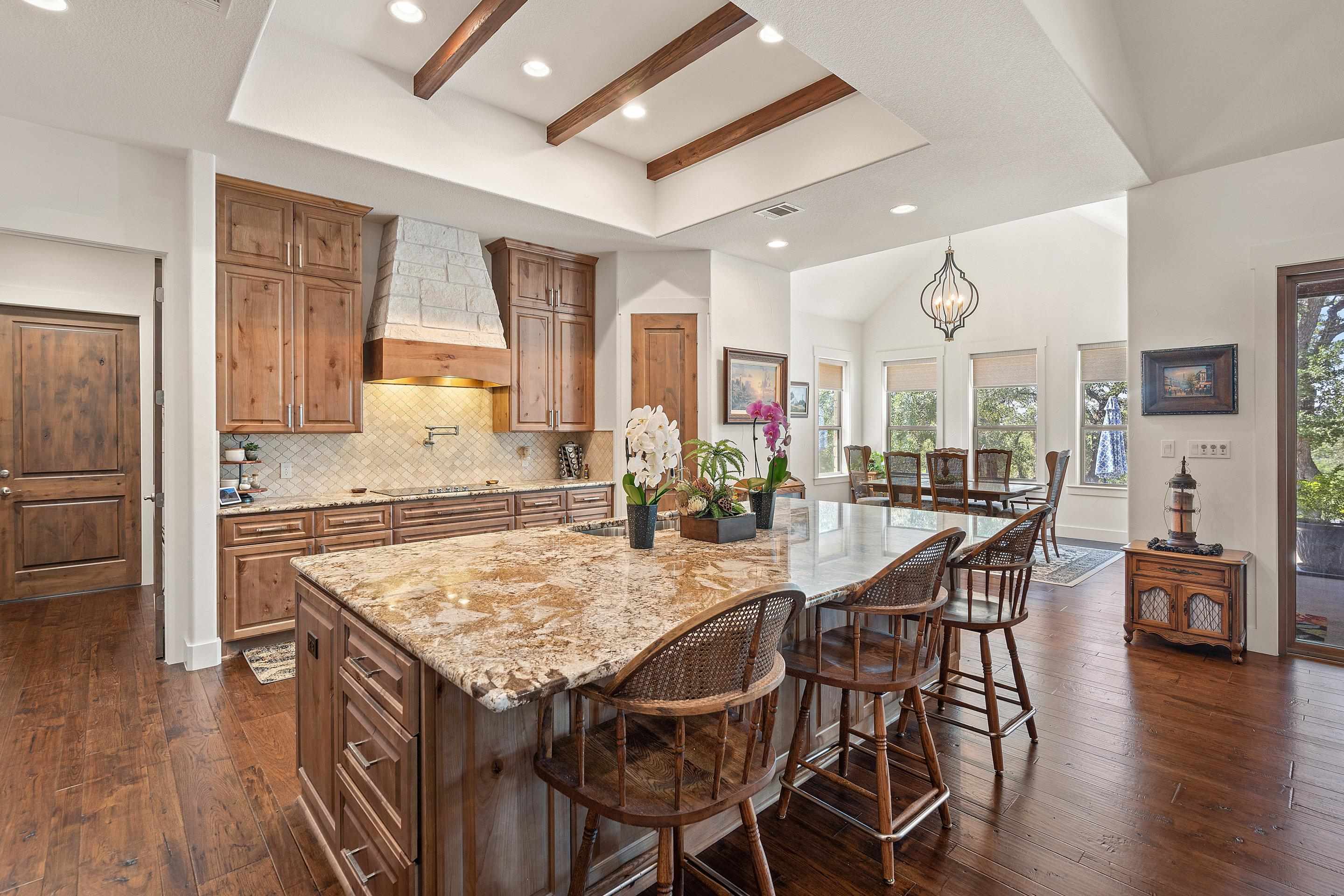 175 Scenic Ridge Drive Spicewood, TX 78669 - Photo 11 of 30 a kitchen with stainless steel appliances granite countertop table chairs sink and wooden floor