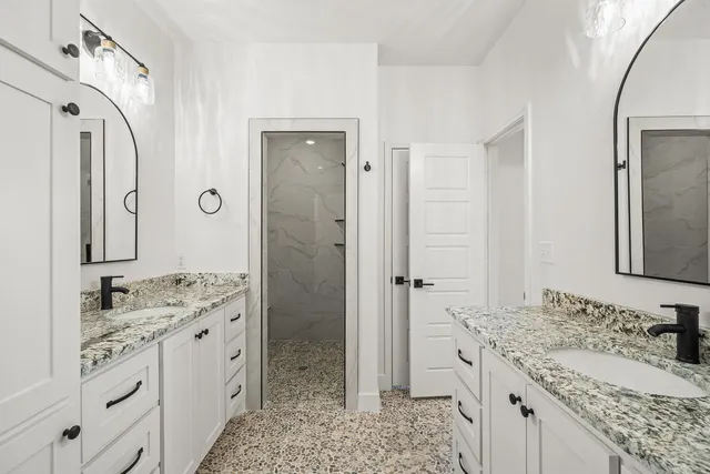 a bathroom with a granite countertop sink a mirror a vanity and a shower