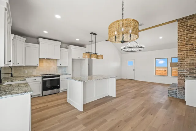 a kitchen with stainless steel appliances granite countertop a refrigerator a stove and a wooden floors