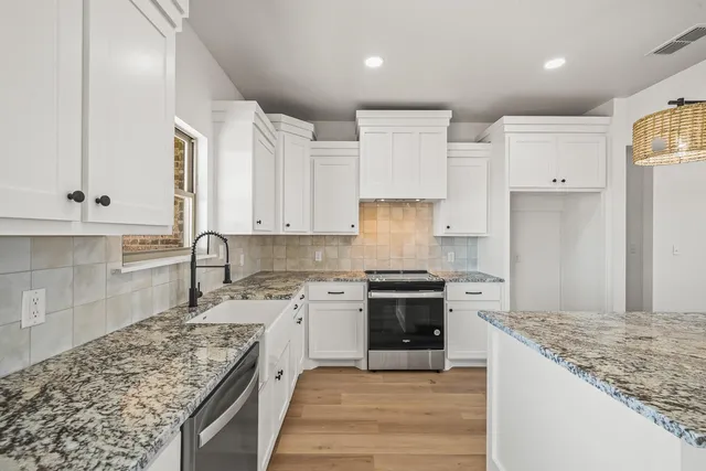 a large kitchen with stainless steel appliances granite countertop a stove a sink and a refrigerator