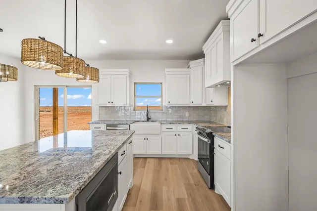 a kitchen with stainless steel appliances granite countertop a stove oven and white cabinets