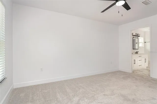 an empty room with windows and ceiling fan