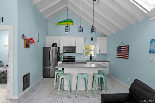 a kitchen with stainless steel appliances granite countertop a dining table chairs refrigerator and sink