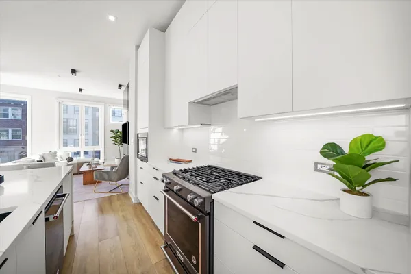 a kitchen with a stove a faucet cabinets and wooden floor