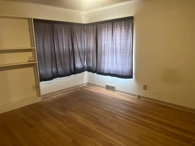 an empty room with wooden floor and entrance