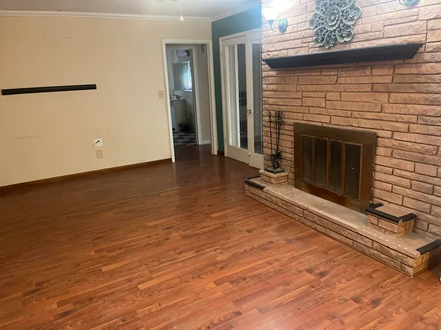 an empty room with wooden floor a fireplace and windows