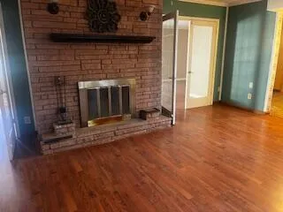 an empty room with wooden floor and fireplace