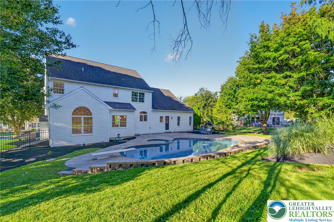 3130 Muirfield Road Center Valley, PA 18034 - Photo 60 of 63 A spacious backyard patio wraps around a curved in-ground pool framed by mature shade trees.