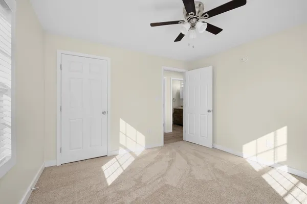 a view of a room with a ceiling fan and carpet