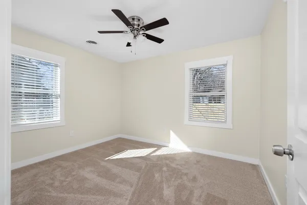a view of a big room with windows and chandelier fan
