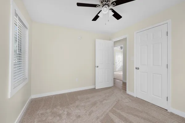 a view of an empty room and chandelier fan