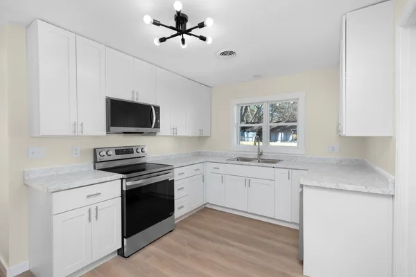 a kitchen with granite countertop a sink stainless steel appliances and white cabinets