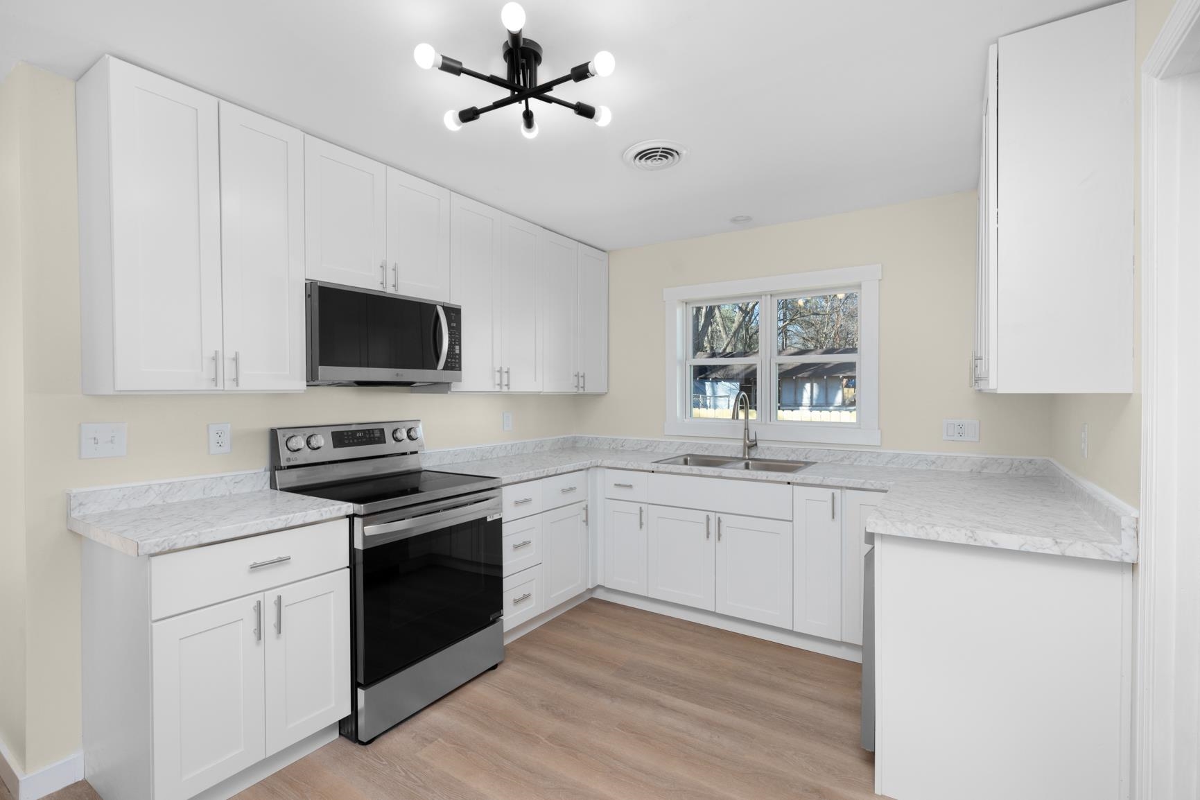 114 Boyce Avenue Covington, TN 38019 - Photo 8 of 24 a kitchen with granite countertop a sink stainless steel appliances and white cabinets