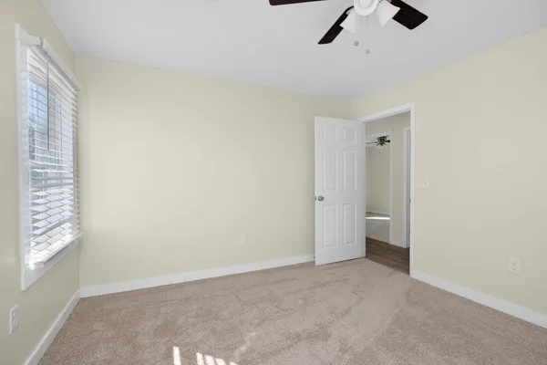 an empty room with windows and fan