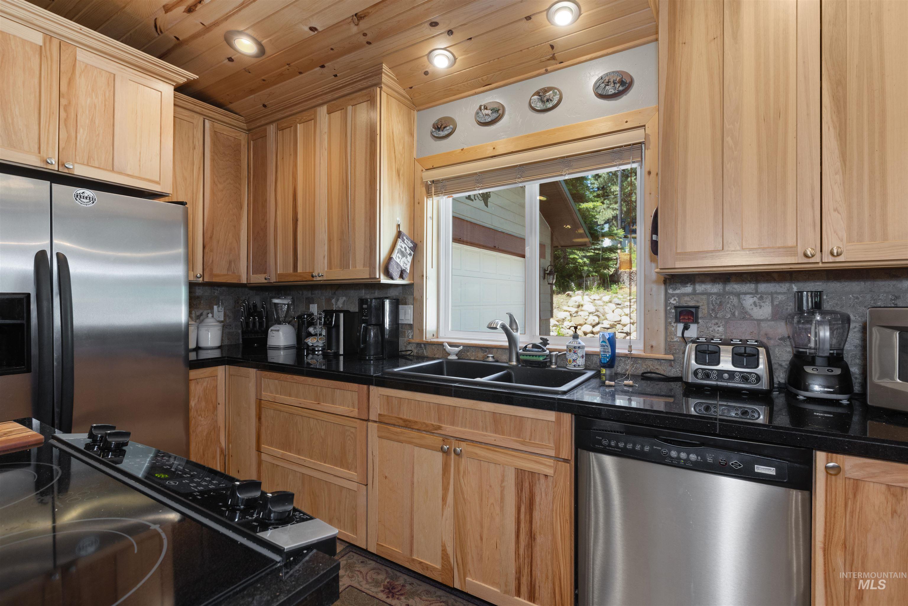 1 Miller Lane Cascade, ID 83611 - Photo 13 of 39 Kitchen featuring stainless steel appliances, dark countertops, decorative backsplash, light brown cabinetry, and wood ceiling