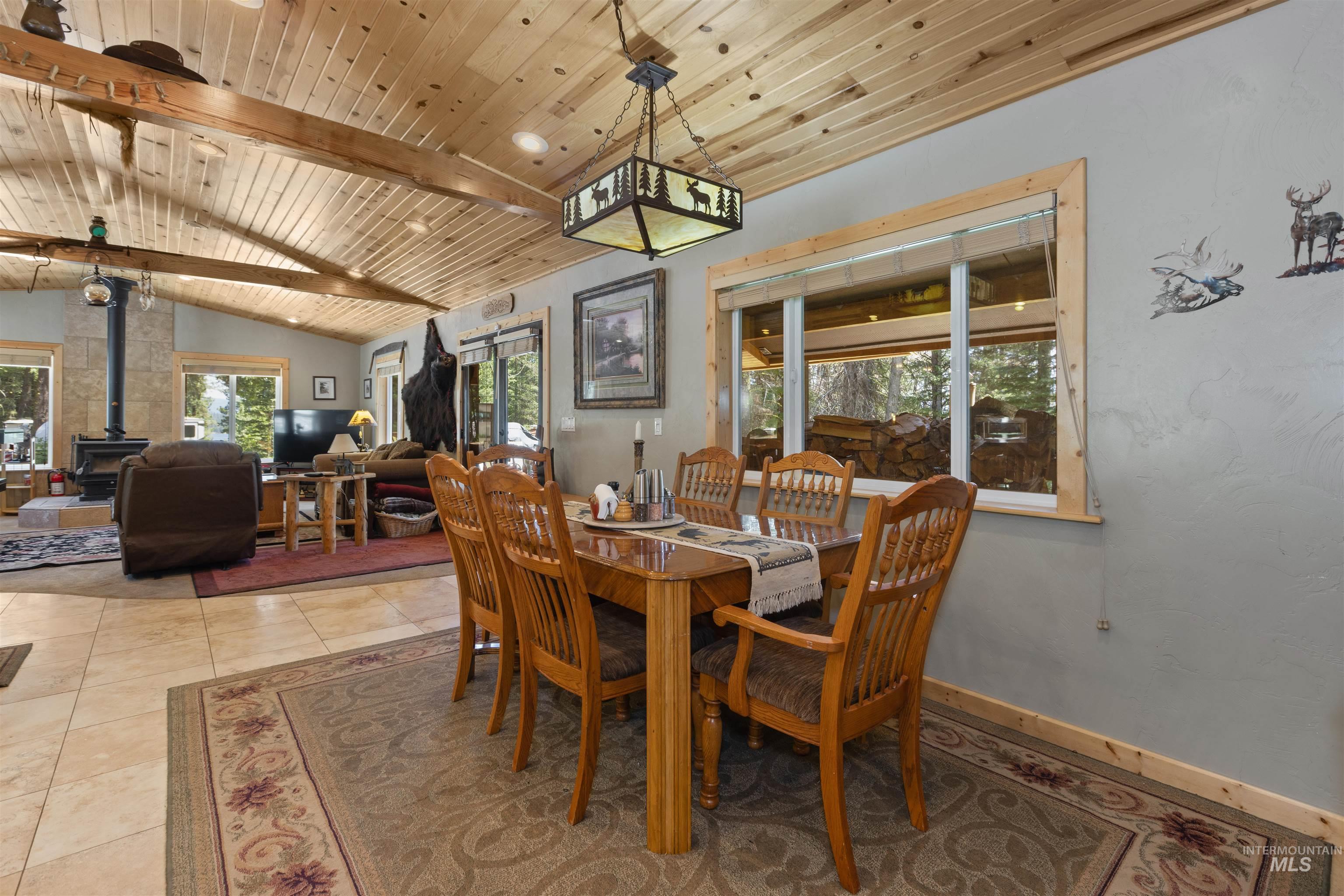 1 Miller Lane Cascade, ID 83611 - Photo 15 of 39 Dining space featuring a wood stove, wood ceiling, and light tile patterned floors