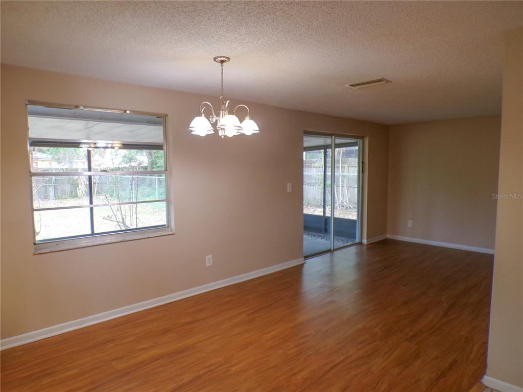 1123 Foggy Ridge Parkway Lutz, FL 33559 - Photo 9 of 18 an empty room with wooden floor chandelier and windows