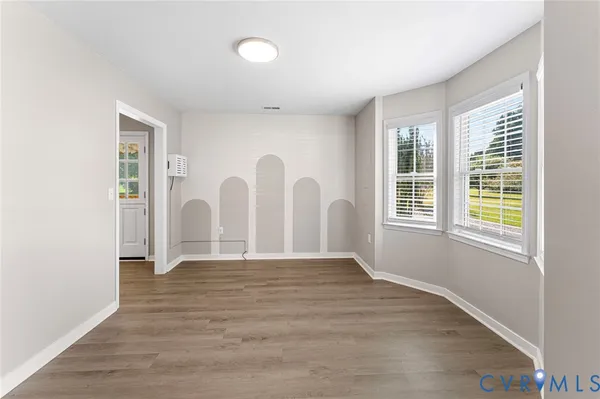 a view of an empty room with wooden floor and window