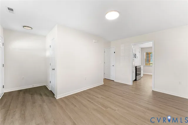 an empty room with wooden floor and windows
