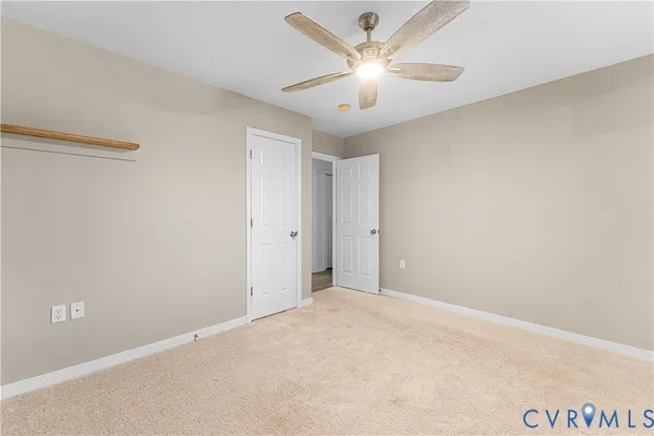 an empty room with a chandelier fan and windows
