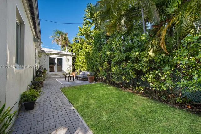 a view of a patio with table and chairs potted plants and floor to ceiling window