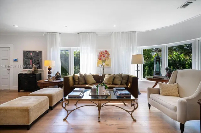 a living room with furniture floor to ceiling window and wooden floor
