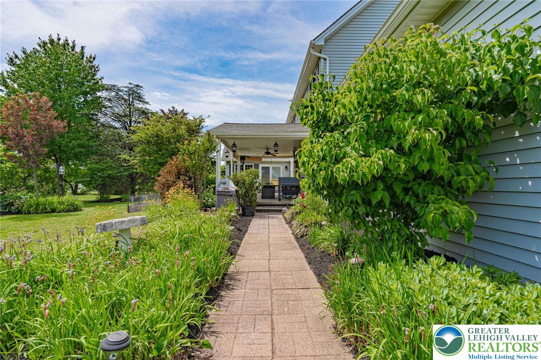 4542 Springfield Drive Coplay, PA 18037 - Photo 60 of 89 A charming walkway leads to a covered porch, surrounded by lush landscaping and mature trees.