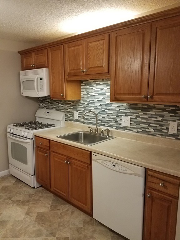 549 Pine Street, Unit 1 Lowell, MA 01851 - Photo 1 of 12 a kitchen with cabinets a sink and appliances