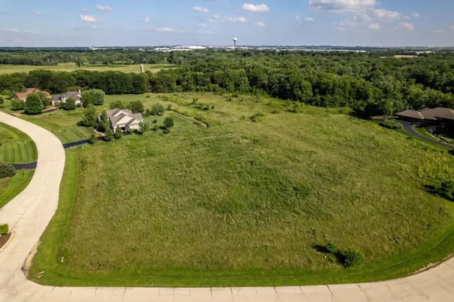 an aerial view of a residential houses with outdoor space and trees all around