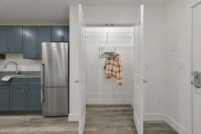 a view of a refrigerator in kitchen and an empty room