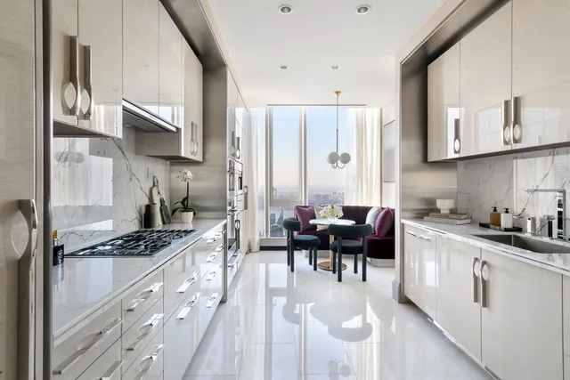 a kitchen with stainless steel appliances kitchen island granite countertop a stove top oven a sink dishwasher and white cabinets with wooden floor