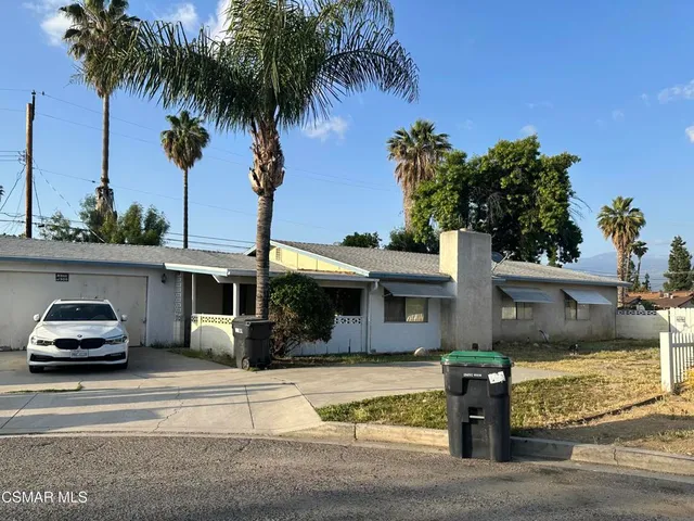 a front view of multiple houses with palm trees
