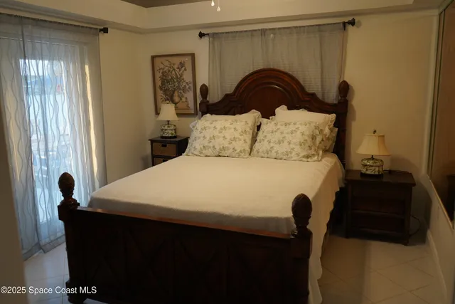 a bed sitting in a bedroom next to a window and a mirror