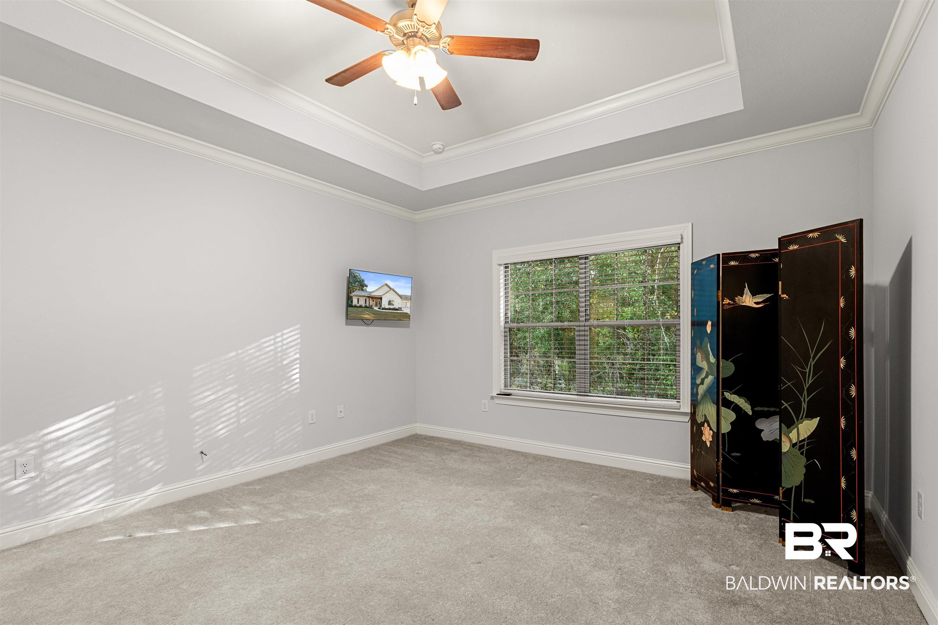 702 Holmes Avenue, Unit 702 Foley, AL 36535 - Photo 18 of 33 Unfurnished room featuring ceiling fan, light colored carpet, crown molding, and a tray ceiling