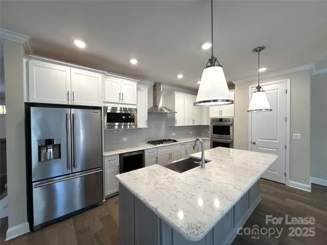 a kitchen with stainless steel appliances granite countertop a refrigerator a sink and a stove