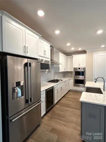a kitchen with stainless steel appliances granite countertop a refrigerator a stove and a sink