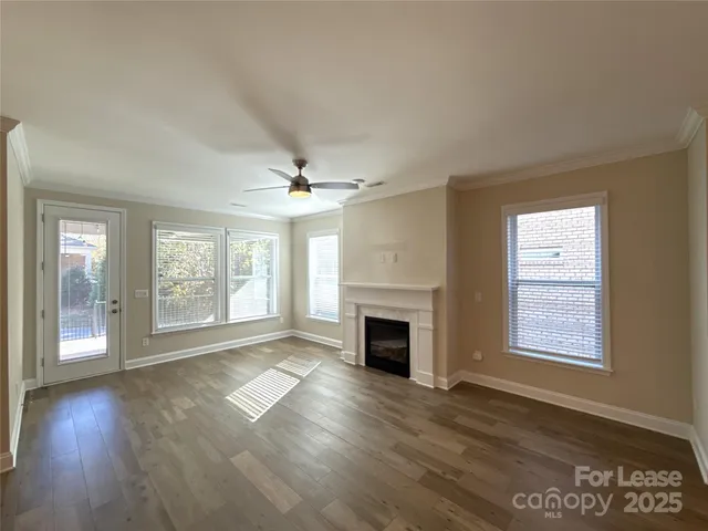 an empty room with wooden floor fireplace and windows