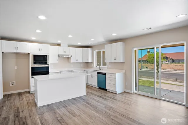a kitchen with white cabinets stainless steel appliances and a window