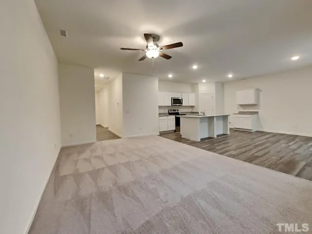 a view of an empty room and kitchen view