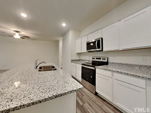 a kitchen with granite countertop a sink a stove and cabinets