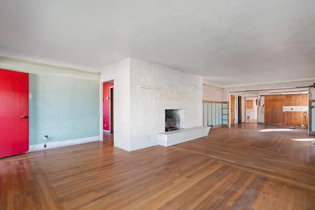 a view of empty room with wooden floor and fireplace