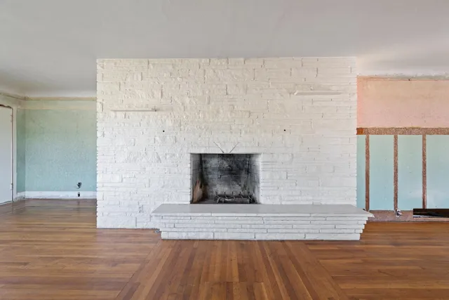 a view of a livingroom with wooden floor and a fireplace