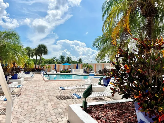 a view of swimming pool with lawn chairs and plants