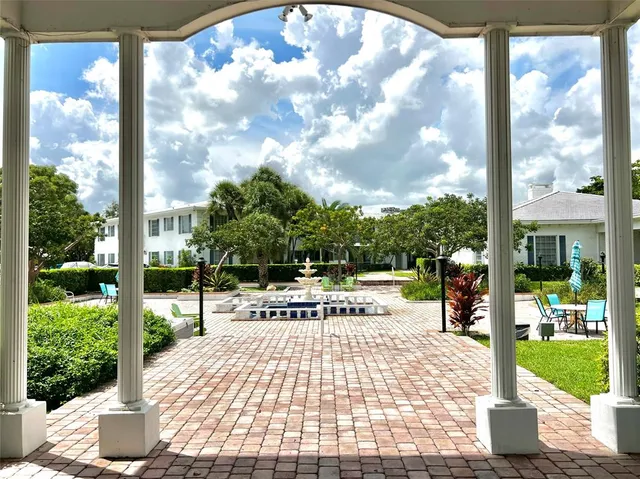 a view of a patio with table and chairs potted plants and large tree