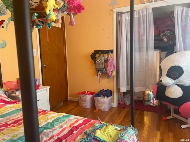 a spacious bedroom with a bed and wooden floor