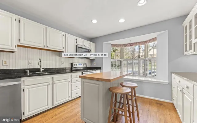 a kitchen with stainless steel appliances granite countertop a stove a sink and white cabinets with wooden floor