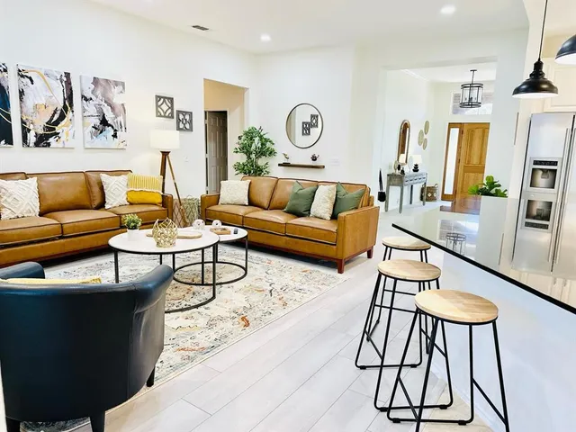 a living room with furniture kitchen view and a large window