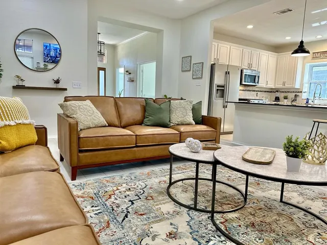 a living room with furniture a rug and kitchen view